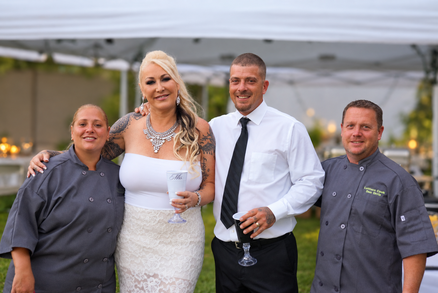 Dan and Chiara in chef jackets with a bride and groom at a wedding