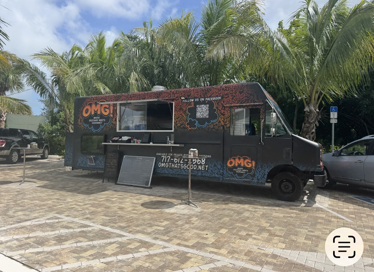 Current OMG food truck with its serving window open beneath palm trees
