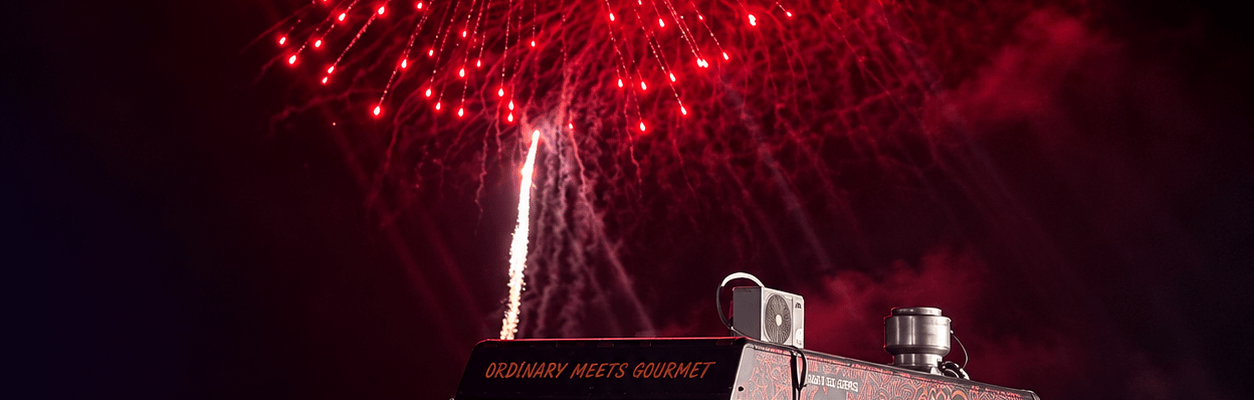 OMG food truck beneath red and gold fireworks at an evening event